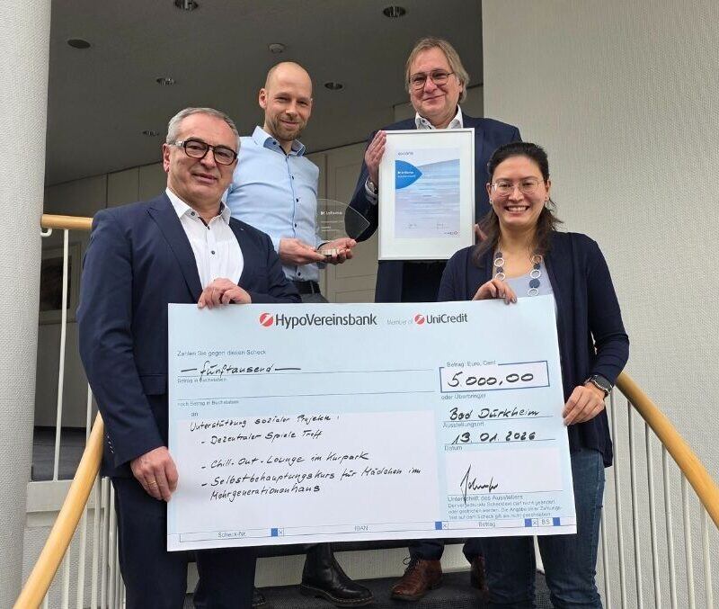 Überreichung des Spendenschecks an den Gewinner des Axians Infoma Innovationspreises; Vertreter der Stadt Bad Dürkheim nehmen den Scheck lächelnd entgegen.