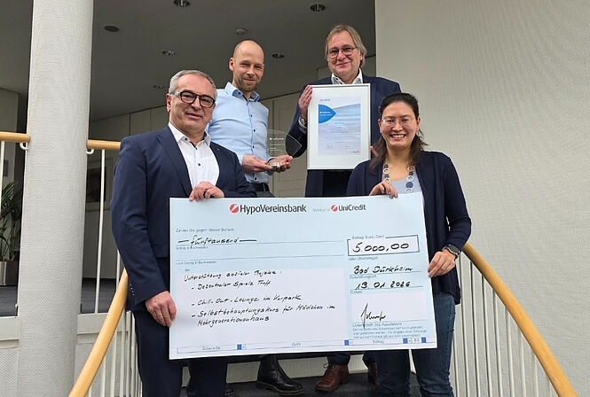 Überreichung des Spendenschecks an den Gewinner des Axians Infoma Innovationspreises; Vertreter der Stadt Bad Dürkheim nehmen den Scheck lächelnd entgegen.