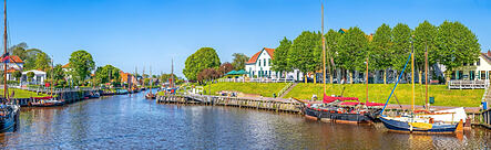 Blick auf den historischen Hafen von Carolinensiel in Ostfriesland mit traditionellen Gebäuden und festgemachten Booten. Das Bild begleitet einen Newstickerbeitrag zur erfolgreichen Einführung der Infoma-Software beim Landkreis Wittmund.
