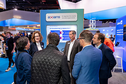 Mitarbeitende von Axians Infoma im Gespräch mit Besucherinnen und Besuchern am Demo-Point auf der Smart Country Convention 2026 in Berlin.